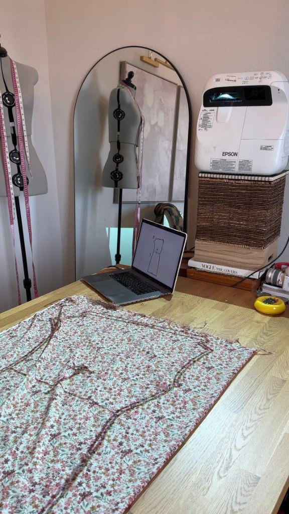 A sewing pattern projected onto floral fabric in a modern sewing studio