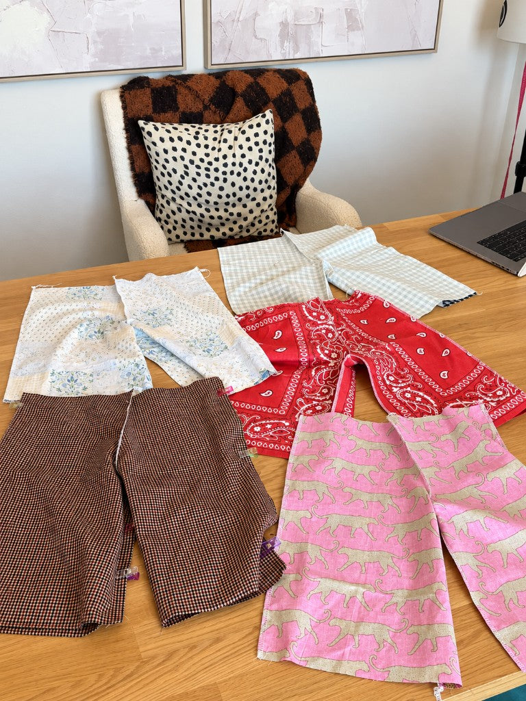 Cut baby pants pieces in several fabrics laid out on a table