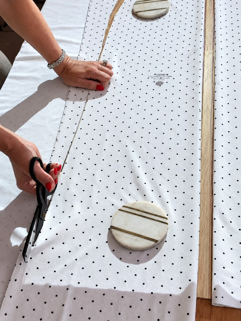 Hands cutting a polka-dot skirt pattern on the fabric