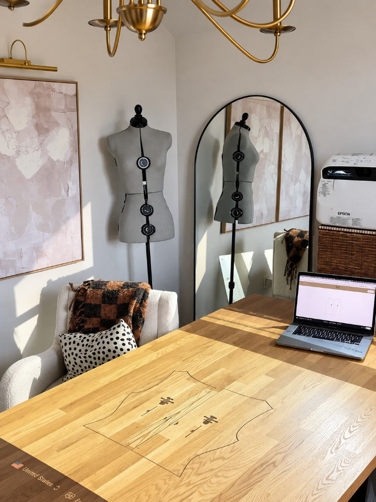 A dress form, projector, and laptop showing a tank pattern on a cutting table